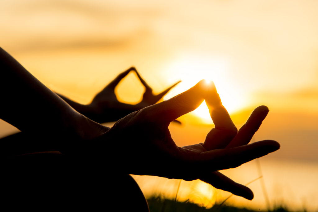 grans en contre jour sur des mains pendant un moment de méditation