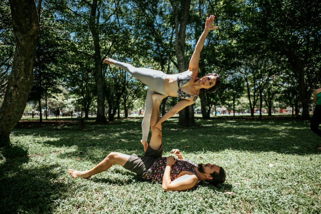 Acroyoga en duo : une femme en équilibre sur les pieds de son partenaire allongé dans l'herbe