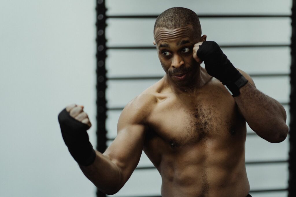 Un homme aux mains bandées en garde de boxe, en plein shadow boxing dans une salle