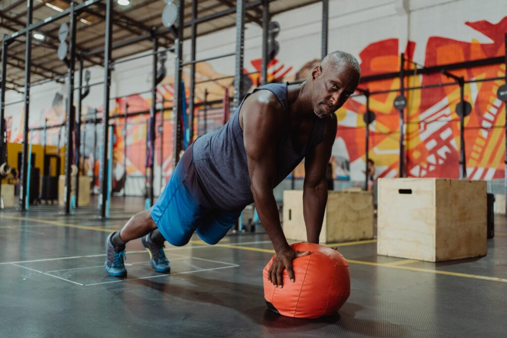 Entraînement fonctionnel : un homme en appui sur un medecine-ball dans une salle de cross training