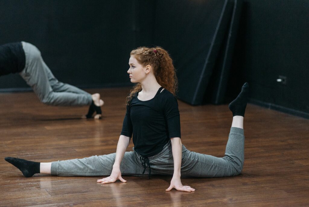Cours de souplesse : une jeune femme fait le grand écart sur le parquet d'un studio